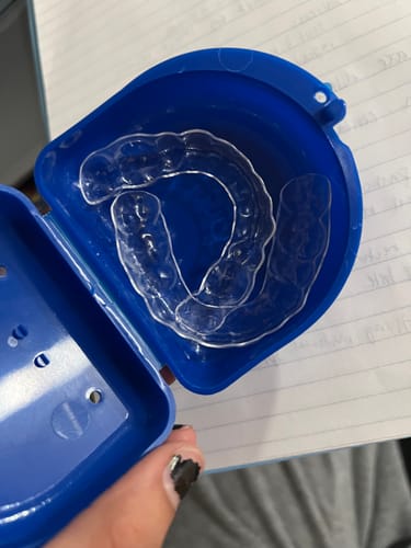 Customer holding an open blue case showing the clear Upper and Lower Retainers Set.