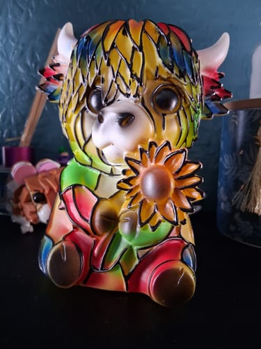 Reviewer's colorful Highland Cow LED Night Light. The mosaic-style resin figurine sits on a table holding a sunflower.