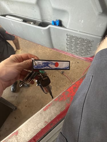 Customer holding their new TOKYO WAVE JET TAG attached to a set of keys in a garage.