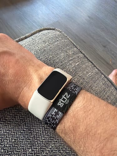 Reviewer wearing the black and white southwest-design Bible Verse Bracelet on their wrist next to a smartwatch.