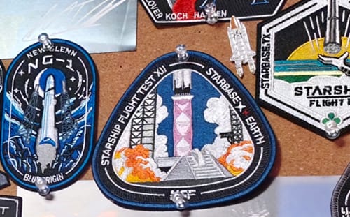 Reviewer's Starship Flight 12 Collectors Patch pinned to a corkboard with other patches from their collection.