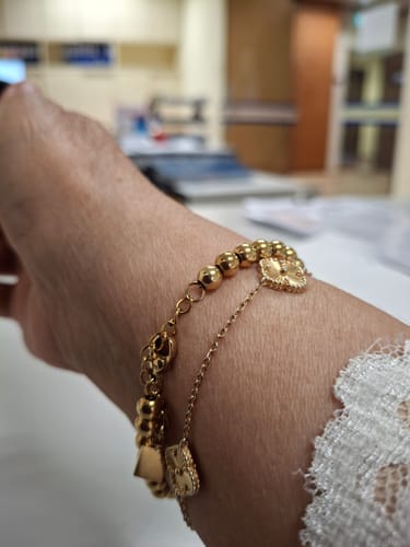 Customer wearing the gold Bold Tasbih Bracelet on their wrist in an office.