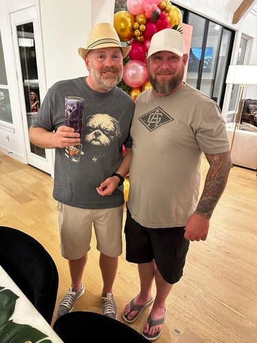 Reviewer wearing the grey Whiskey Shih Tzu Grunge T-Shirt while standing with another person at a party.