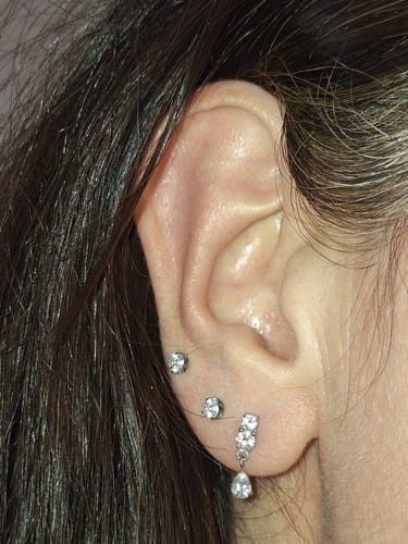 Reviewer's ear wearing the silver Dangle flatback stud in their lowest lobe piercing, among other studs.