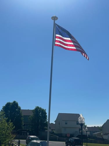 Reviewer's Betsy Ross Flag flying on a tall flagpole against a bright blue sky.