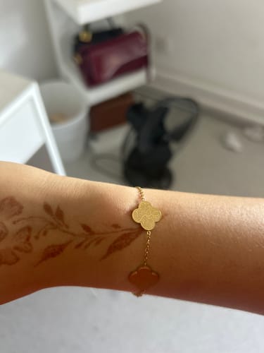 Customer's wrist with a floral henna design, wearing the gold Sabr, Shukr, Tawakkul Bracelet.