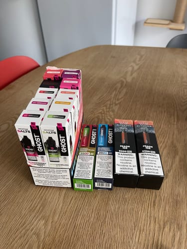 Customer's collection of Ghost Nic Salt e-liquids in various flavors arranged on a wooden table.