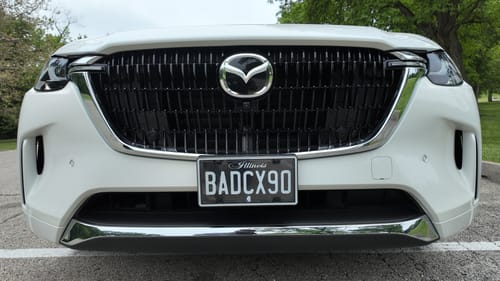 Customer's black Illinois license plate with 'BADCX90' mounted on the front of their white vehicle.