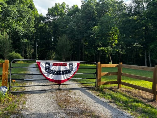 Reviewer's Americana Pleated Fan with Stars displayed on a metal gate with a wooden fence.