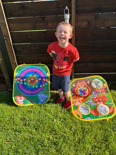 Customer's photo of a smiling child standing outdoors next to two lawn games.