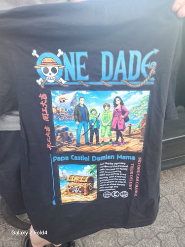 Ein Kunde hält das personalisierte schwarze „ONE DAD“-T-Shirt mit einem farbenfrohen Anime-Druck hoch.
