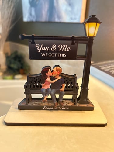 Customer's personalized wooden plaque of a couple kissing on a bench, with names and a 'You & Me WE GOT THIS' sign.