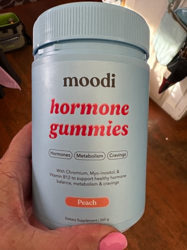 Customer holding the light blue bottle of Moodi Peach Hormone Gummies.