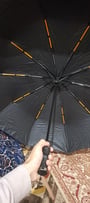 Customer holding their open black folding umbrella, showing the interior frame with orange details.