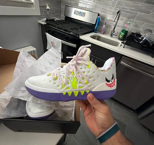 Customer holding their new Joker 2 "Wildcard" shoe, showing the white upper, purple sole, and neon green details.