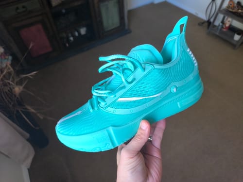 Customer holding a bright turquoise Joker 1 GT SE basketball shoe in their hand.