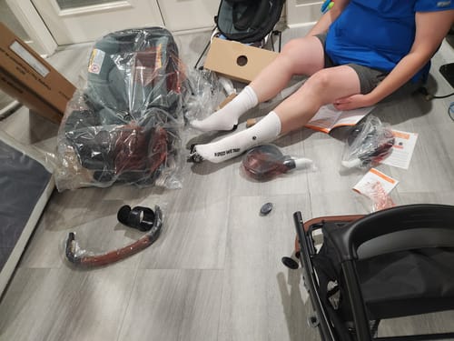 A reviewer wears the Classic Crew Socks while sitting on the floor assembling new baby equipment.