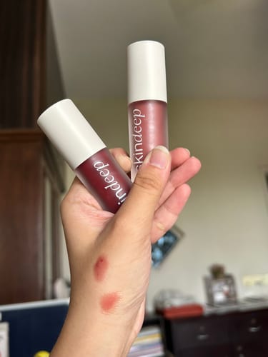 Customer holding two Gloss POP™ lip gloss tubes with swatches of the shiny colors on their hand.