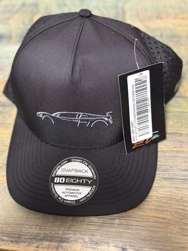 Customer's new black 80Eighty DCG89 Hat on a wooden surface, showing the embroidered car outline and perforated panels.
