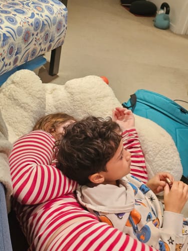 A customer's child relaxing in the striped Blush + Boysenberry Long PJ Set.