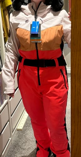 Reviewer wearing the colorblock one-piece ski suit with a light-colored top and vibrant red pants.