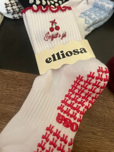Customer's close-up of the white 'I'm Just A Girl' sock, showing the red cherry embroidery, scalloped trim, and non-slip grips.