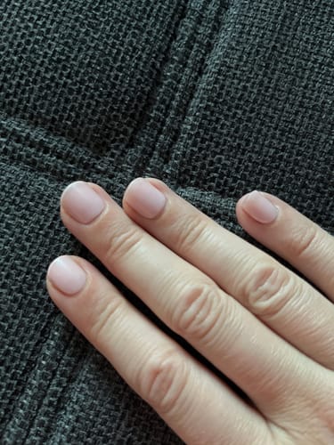 Hand einer Rezensentin, die die dezenten 'Rosé Teint' UV Gel Nail Wraps auf kurzen Nägeln trägt.