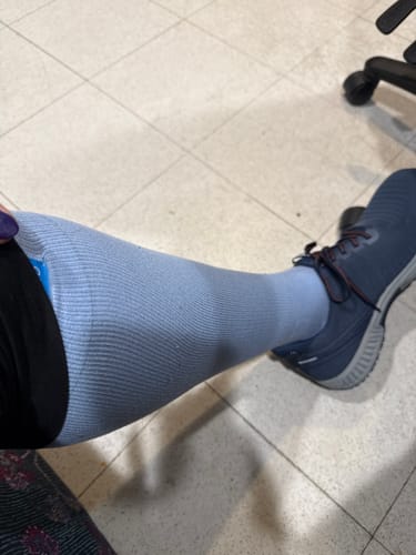Customer wearing the Spring Sky Blue compression sock, pulled up high on the leg with a dark sneaker.