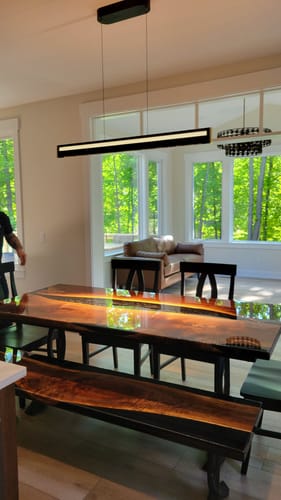 Reviewer's sleek Matrix Light Bar installed over a wooden dining table in a room with a large window view.