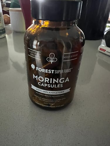 Customer's brown glass bottle of Organic Moringa Capsules sitting on a kitchen counter.