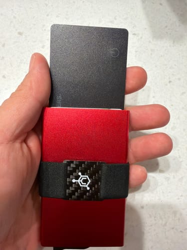 Customer holding a red wallet with the black SPOTMINDERS Tracking Card visible.