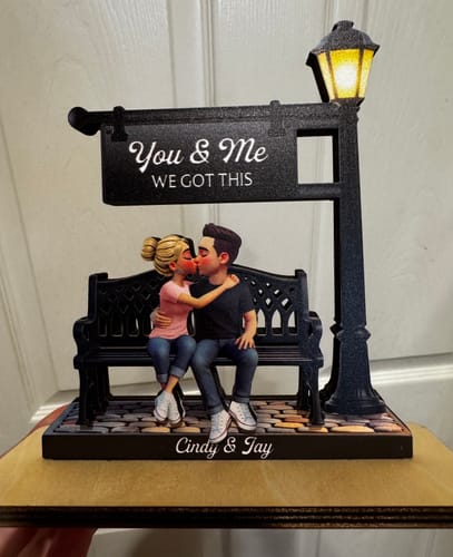 Customer's personalized wooden plaque with a couple kissing on a bench under a lamppost, personalized with 'Cindy & Jay'.