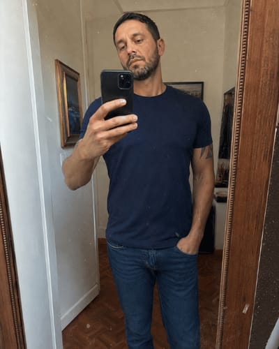 Recensore che indossa la T-SHIRT VARLANI® blu in un selfie allo specchio per mostrare la vestibilità.