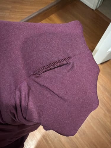 Customer's close-up of a damaged thumbhole on the sleeve of the purple Naked Closed Toe Jumpsuit.