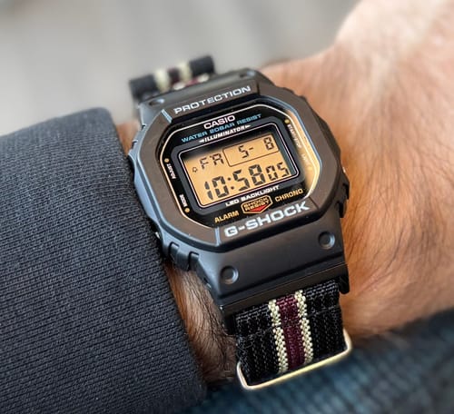 Close-up of a reviewer's Ribbed Mako FN strap in Black, Tan & Red on a black digital watch.