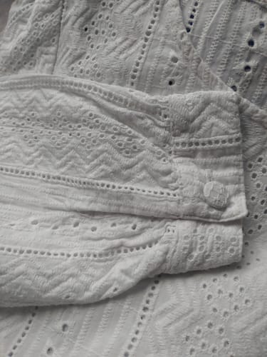 Photo d'un client : Gros plan sur le poignet et la délicate broderie ivoire de la blouse Amarante.