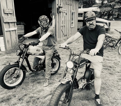 A black and white photo of a customer on their TIGER RE Retro Electric Bike, sitting next to another person on a different bike.