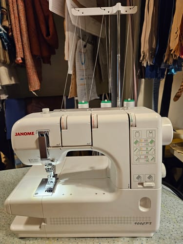 Customer's white Janome 900CPX Coverstitch Machine set up in a sewing room, threaded for a project.
