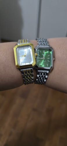 Reviewer's wrist wearing two vintage CLAIRE DE MAINS watches: one two-tone with a white dial, one silver with a green dial.