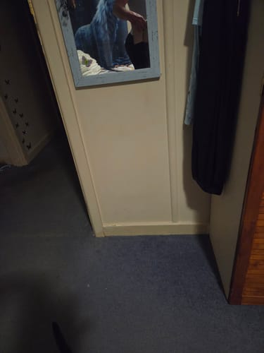 Partial view of a reviewer's reflection in a mirror, wearing the black 3D Anti-Cellulite Leggings.
