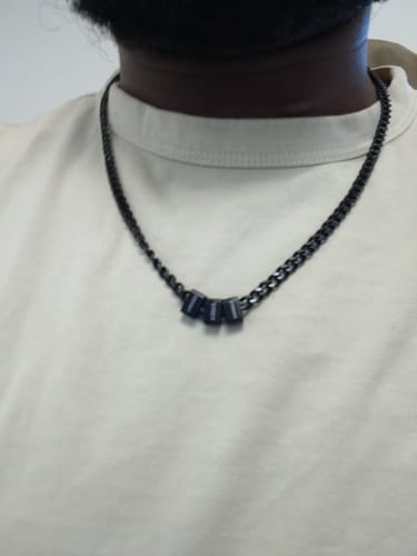 Close-up of a reviewer wearing the black steel Legacy necklace with three personalized beads.