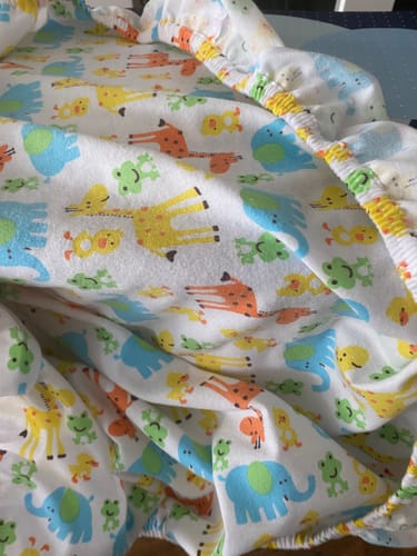 Customer's brushed cotton fabric sewn into a fitted cot sheet with a colorful giraffe and elephant print.