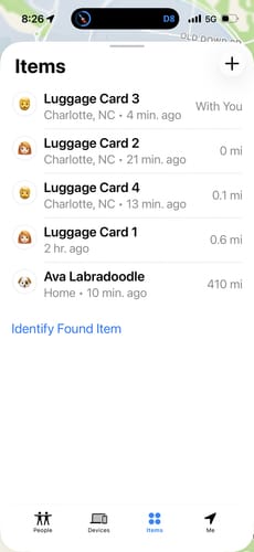 A reviewer's phone screen showing an app tracking the location of several luggage cards on a trip.