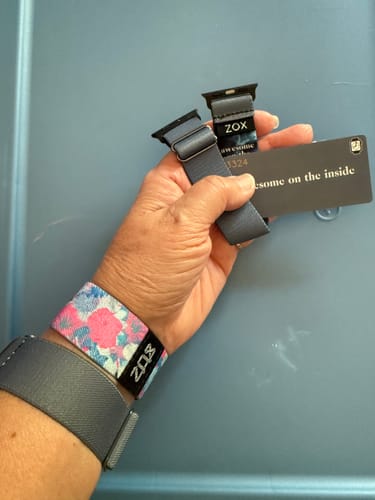 Reviewer holding the grey Denim Awesome on the Inside Watch Band, with other colorful bands on their wrist.