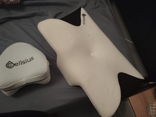 Client montrant le coussin orthopédique pour genoux Cellsius à côté d'un autre oreiller sur un lit.