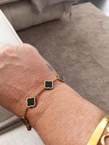 Customer wearing the gold Celine Clover Bracelet with black enamel clovers on their wrist.