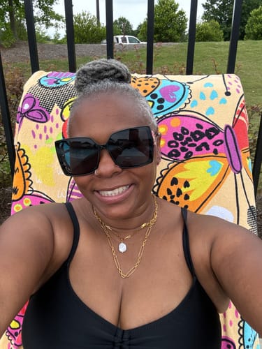 Reviewer smiling while wearing the layered Hanalei Pearl Coin Paperclip Necklace bundle outdoors.