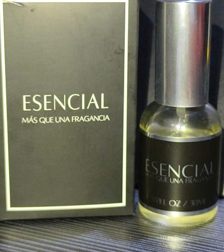 Cliente muestra el perfume Esencial H152. Se ve la botella de vidrio y su empaque negro.