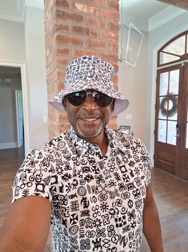 Reviewer wearing the Black and White Adinkra Tribe Symbols Bucket Hat with a matching shirt indoors.