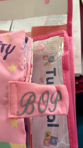 Close-up of customer's pink Hello Potty book with the personalized name 'BOP' embroidered on the strap.